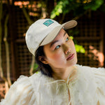 Load image into Gallery viewer, Woman wearing a white cap and light-colored top outdoors with blurred background