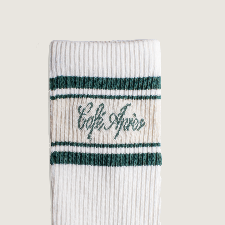 White sock with green stripes and 'Cafe Apres' text on a beige background