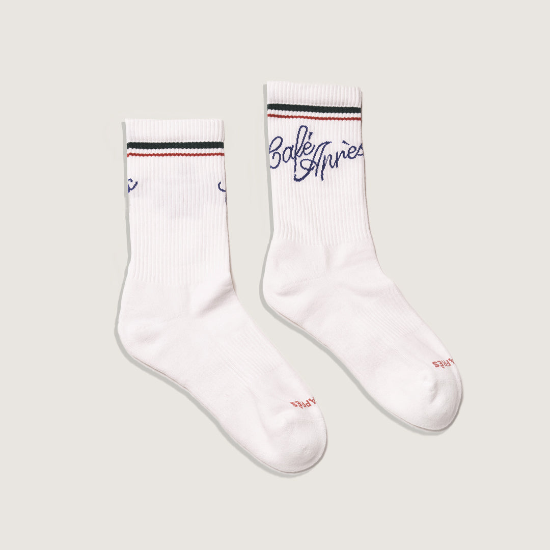 White socks with green and red accents on a light gray background with Café Après logo in blue