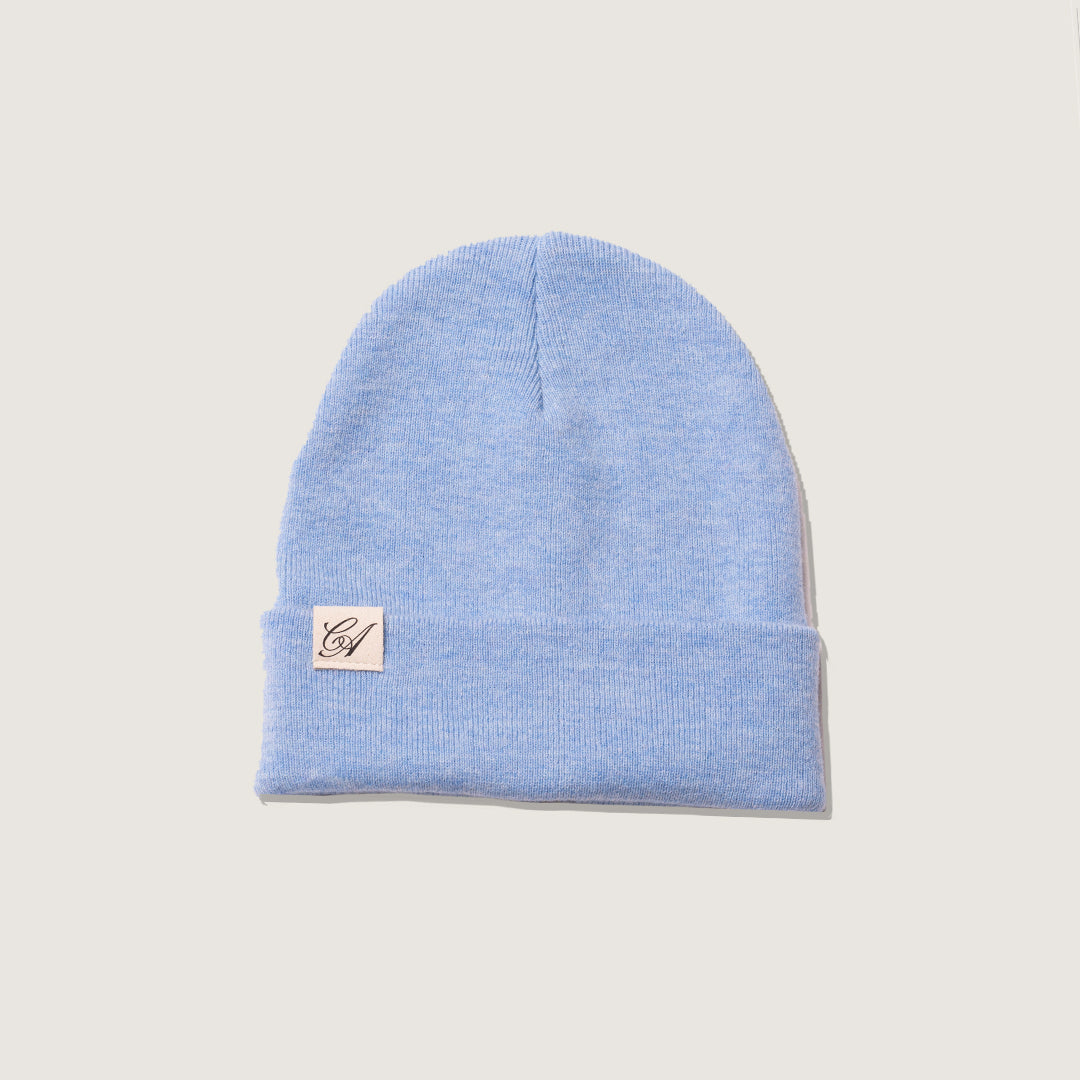Light blue beanie with a brand logo on a beige background