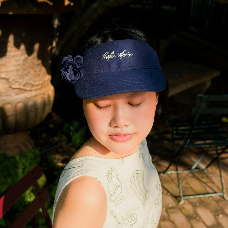 Person wearing a navy visor with floral decoration outdoors
